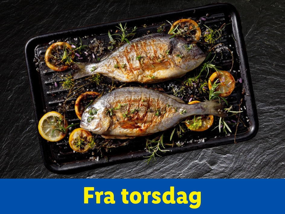 To grillede fisk med citron og krydderurter på en sort grillpande.