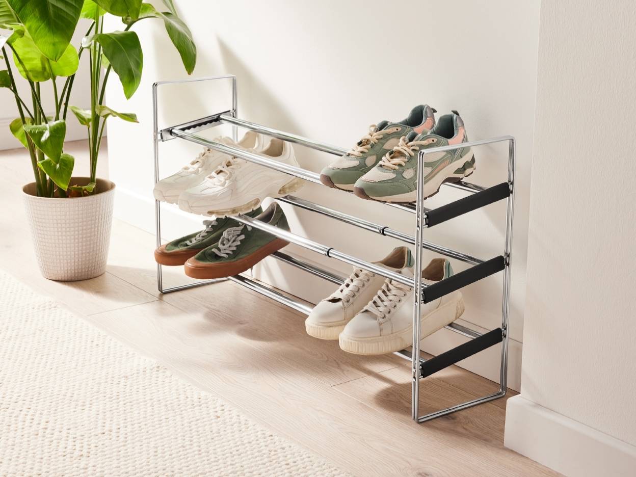 Et skostativ i krom med tre hylder fyldt med forskellige sneakers.