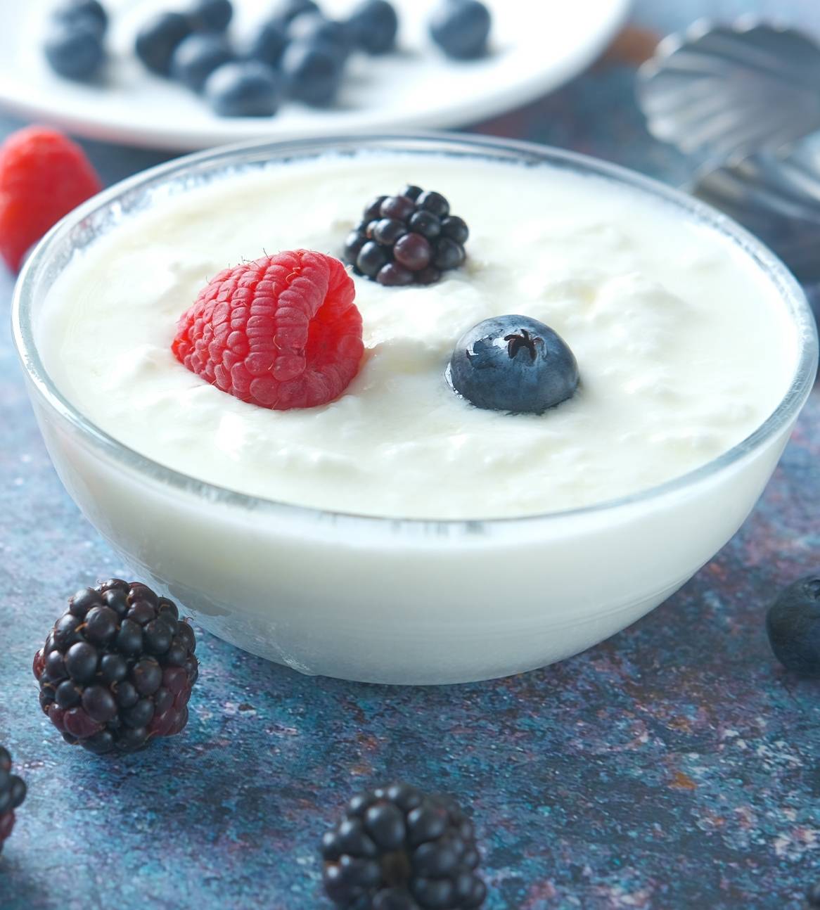 En skål med yoghurt toppet med hindbær, brombær og blåbær.