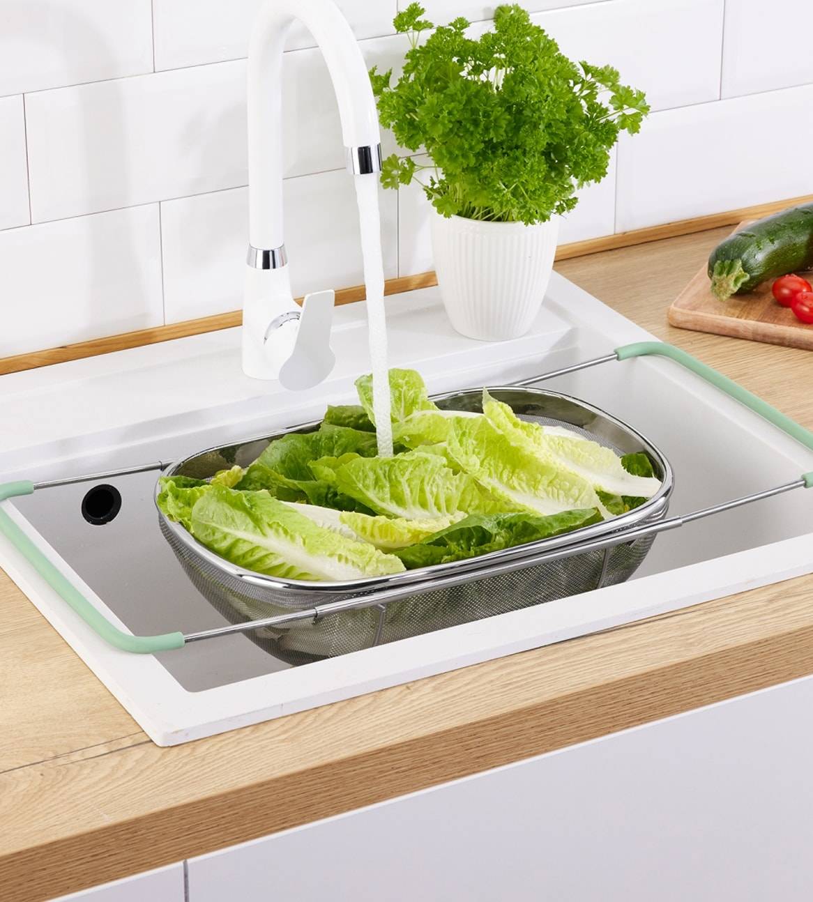 En sammenklappelig køkkensi i rustfrit stål vasker salat i en moderne køkkenvask.