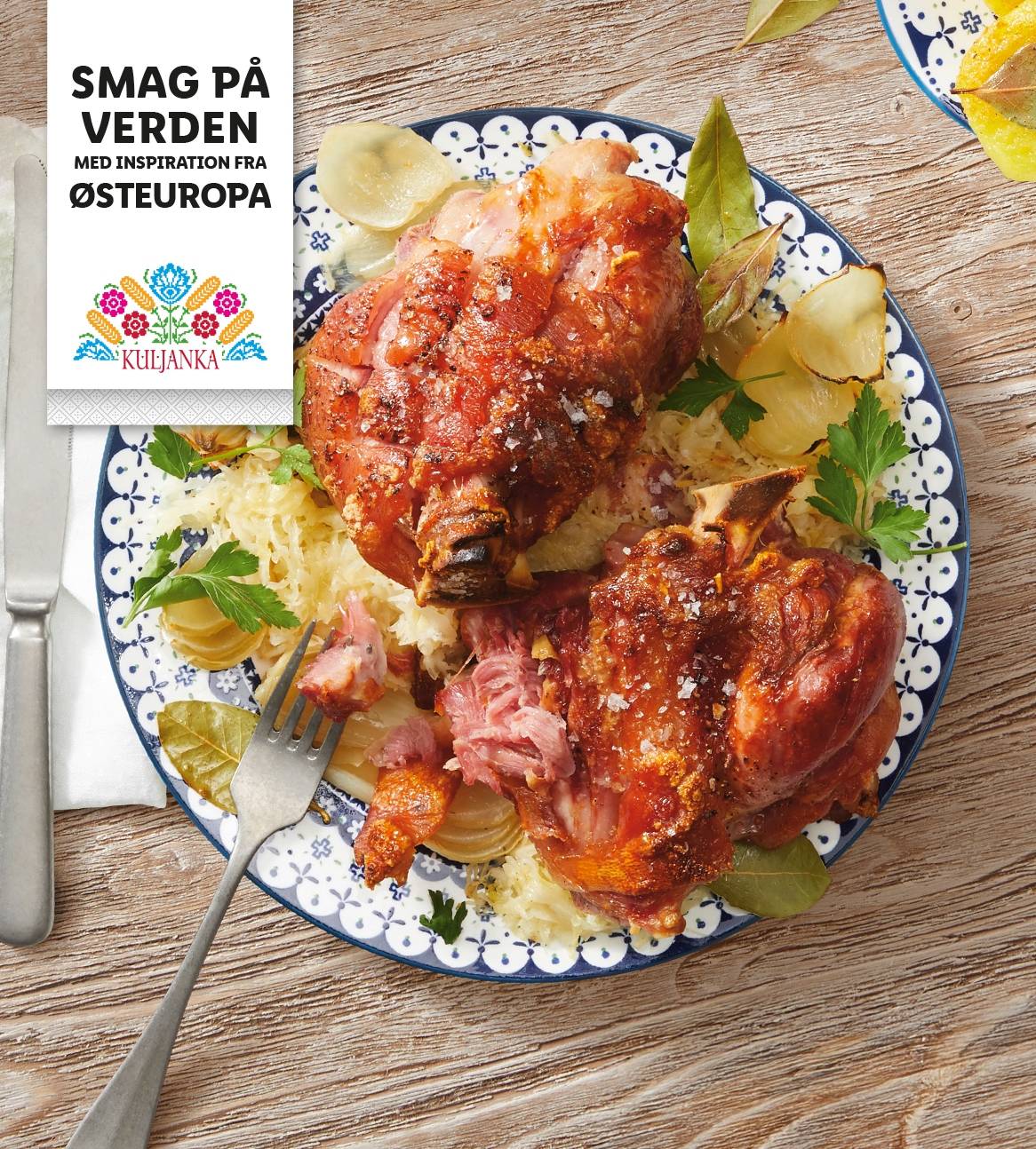 To sprøde svinekæber serveret med surkål på en blå og hvid tallerken.