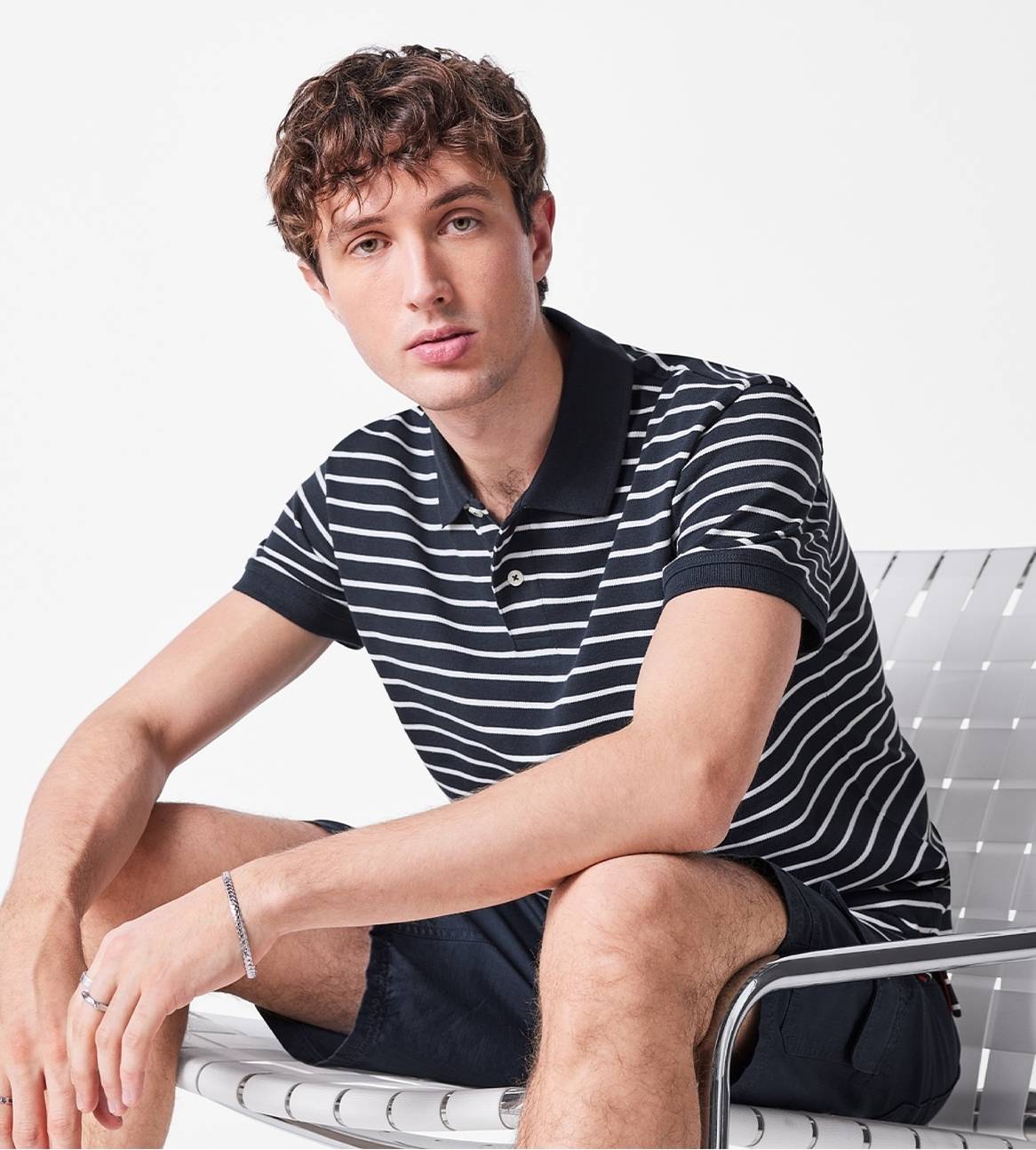 Model iført en navy-hvid stribet polo-skjorte og mørkeblå shorts.