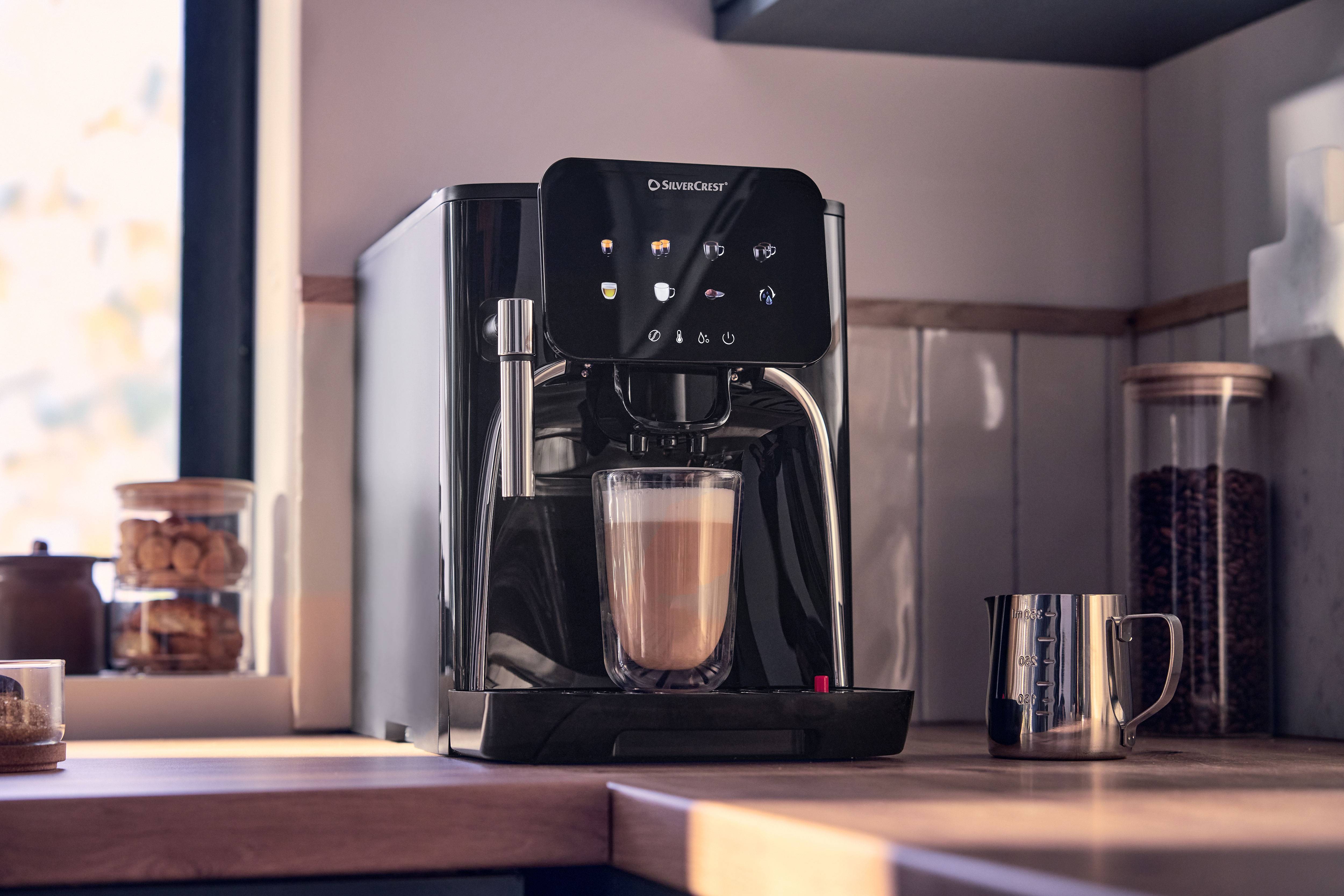 Kaffemaskine med touchskærm, der tilbereder latte i et glas, på en træbordplade.