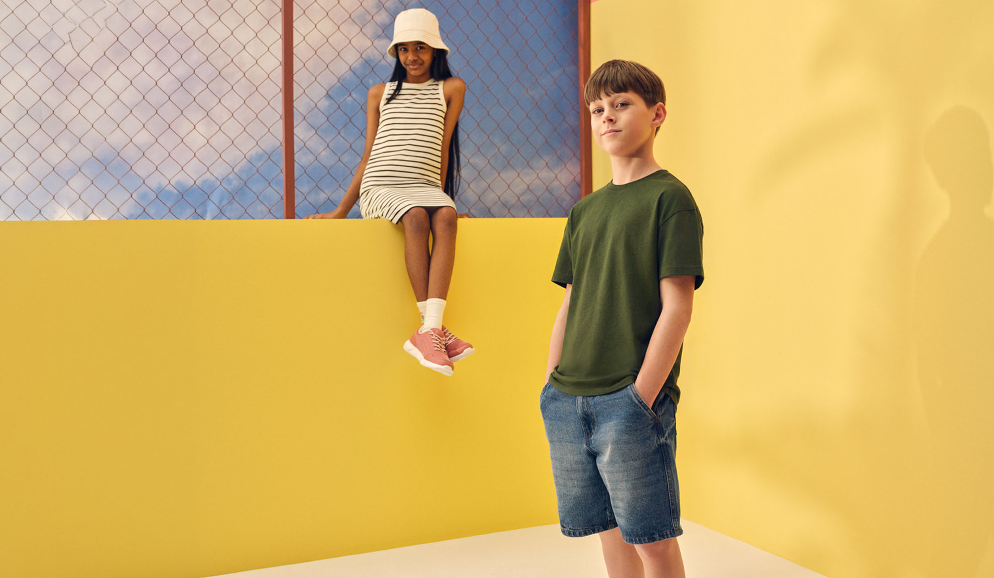 Pige i stribet kjole og dreng i t-shirt og denimshorts.